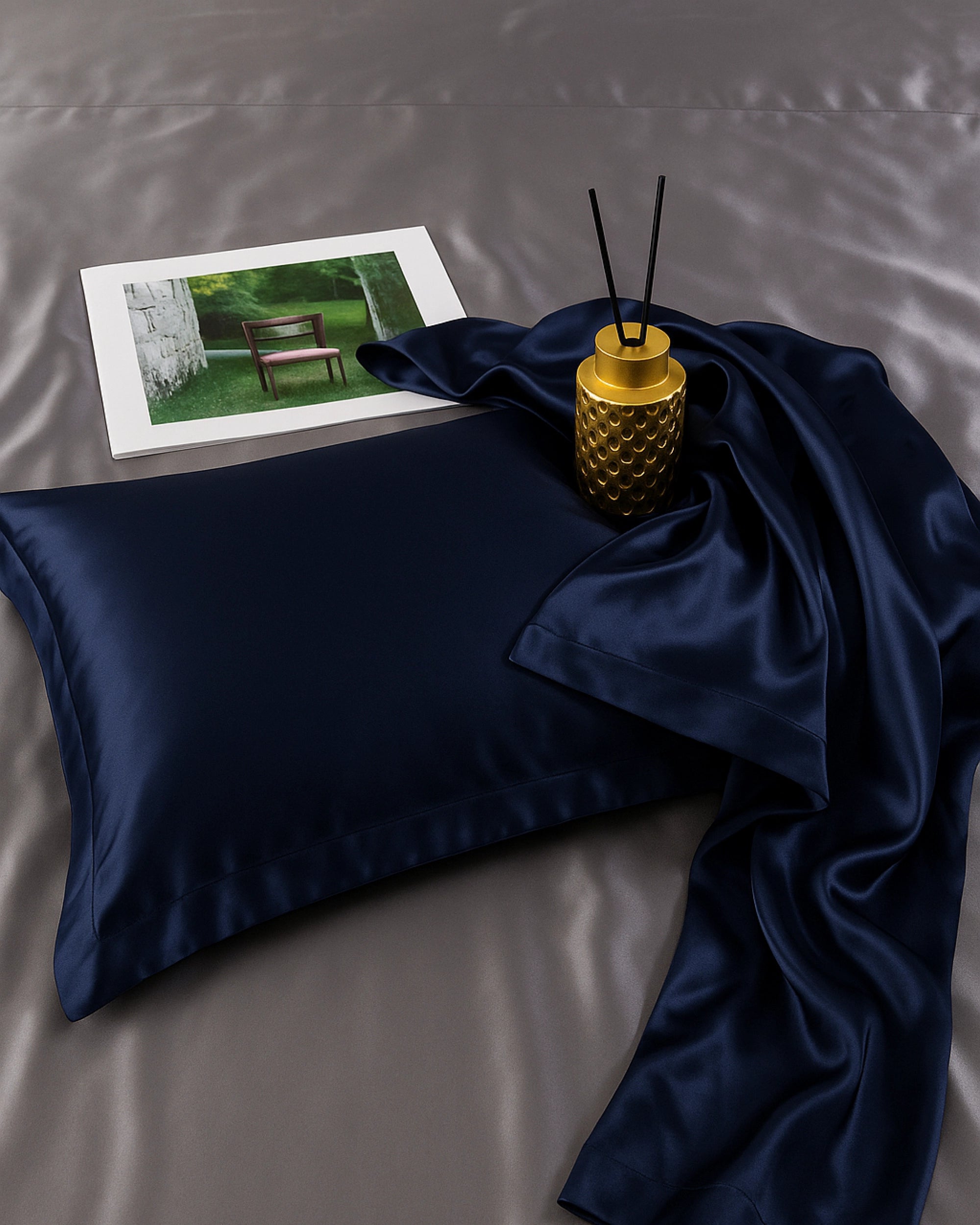Midnight blue satin oxford pillowcase on a smooth surface with decor elements for a luxurious bedding ambiance.