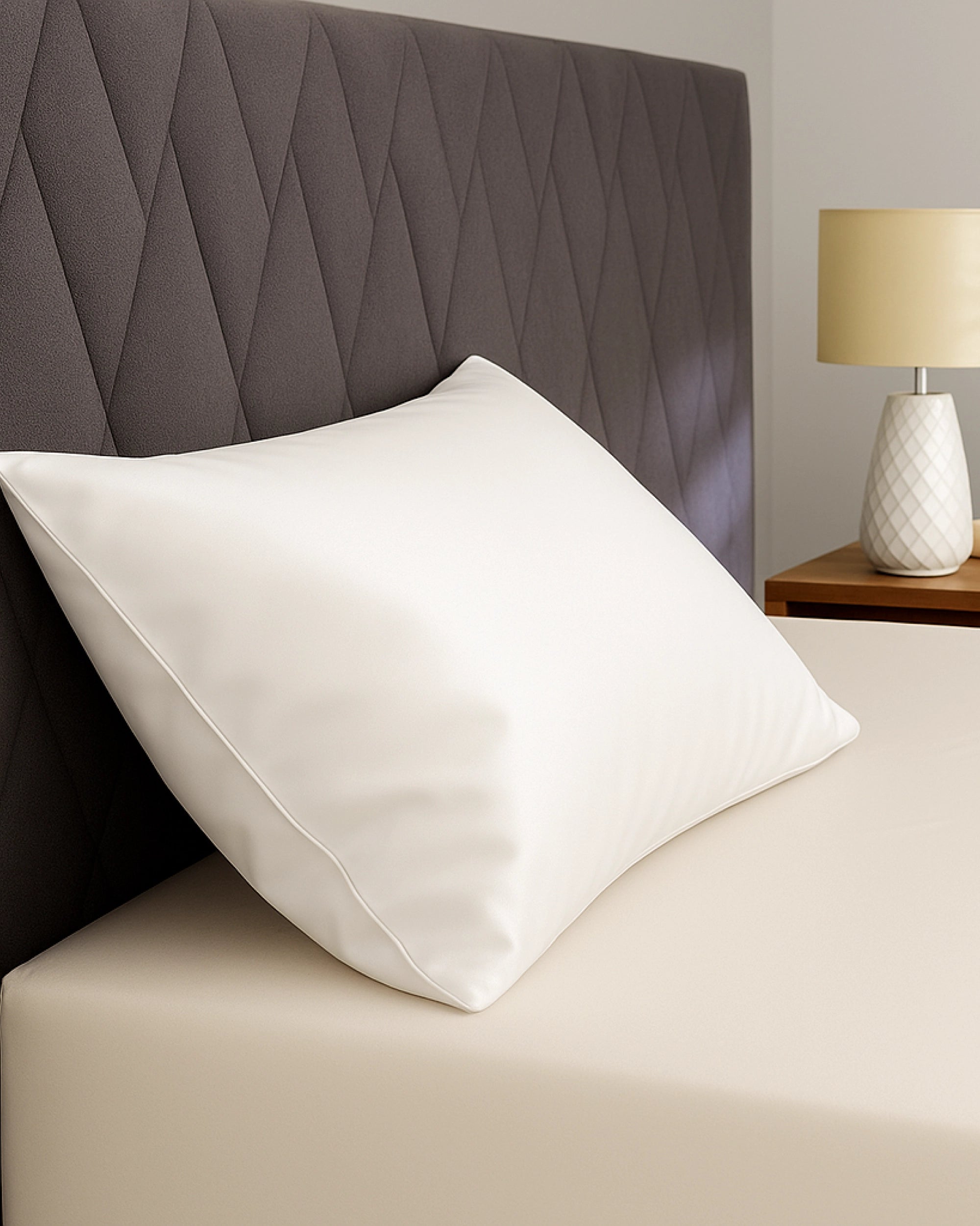 Frost white satin pillowcase on a bed with a modern headboard and bedside lamp, promoting elegance and comfort.