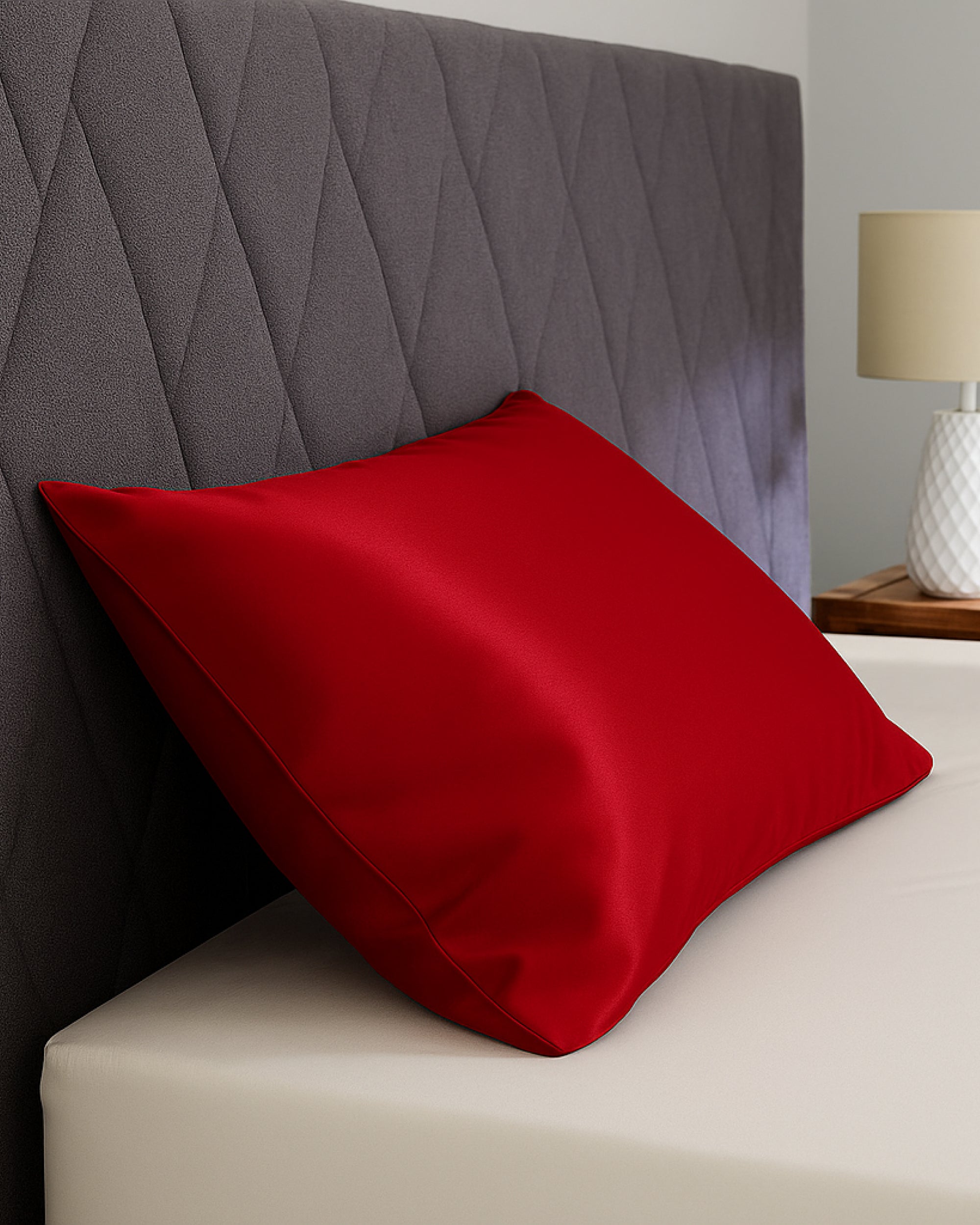 Imperial Red Satin Pillowcase on a bed, offering a bold color and smooth surface for hair and skin.