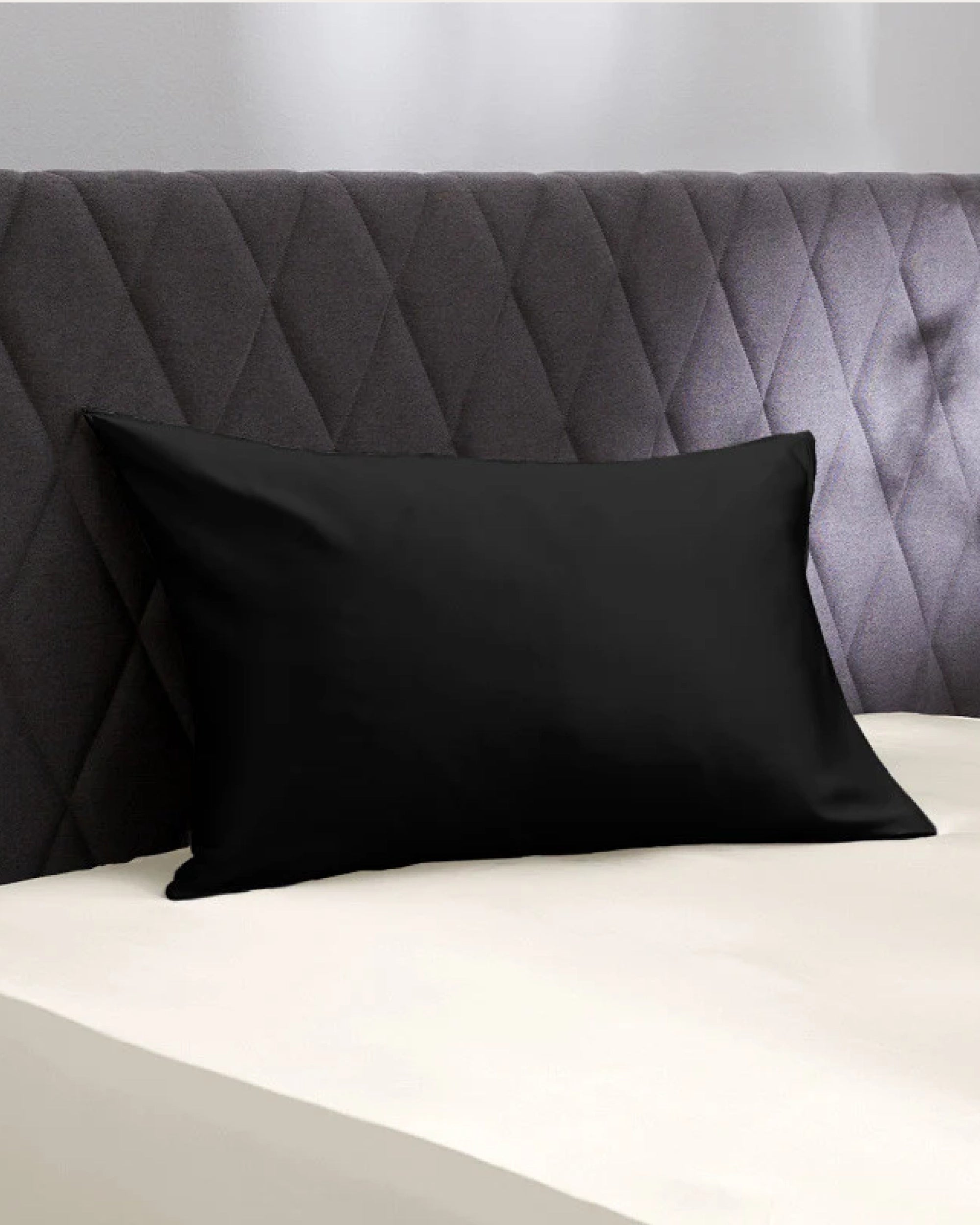 Sleek black velour satin pillowcase on a modern bed with a stylish headboard.