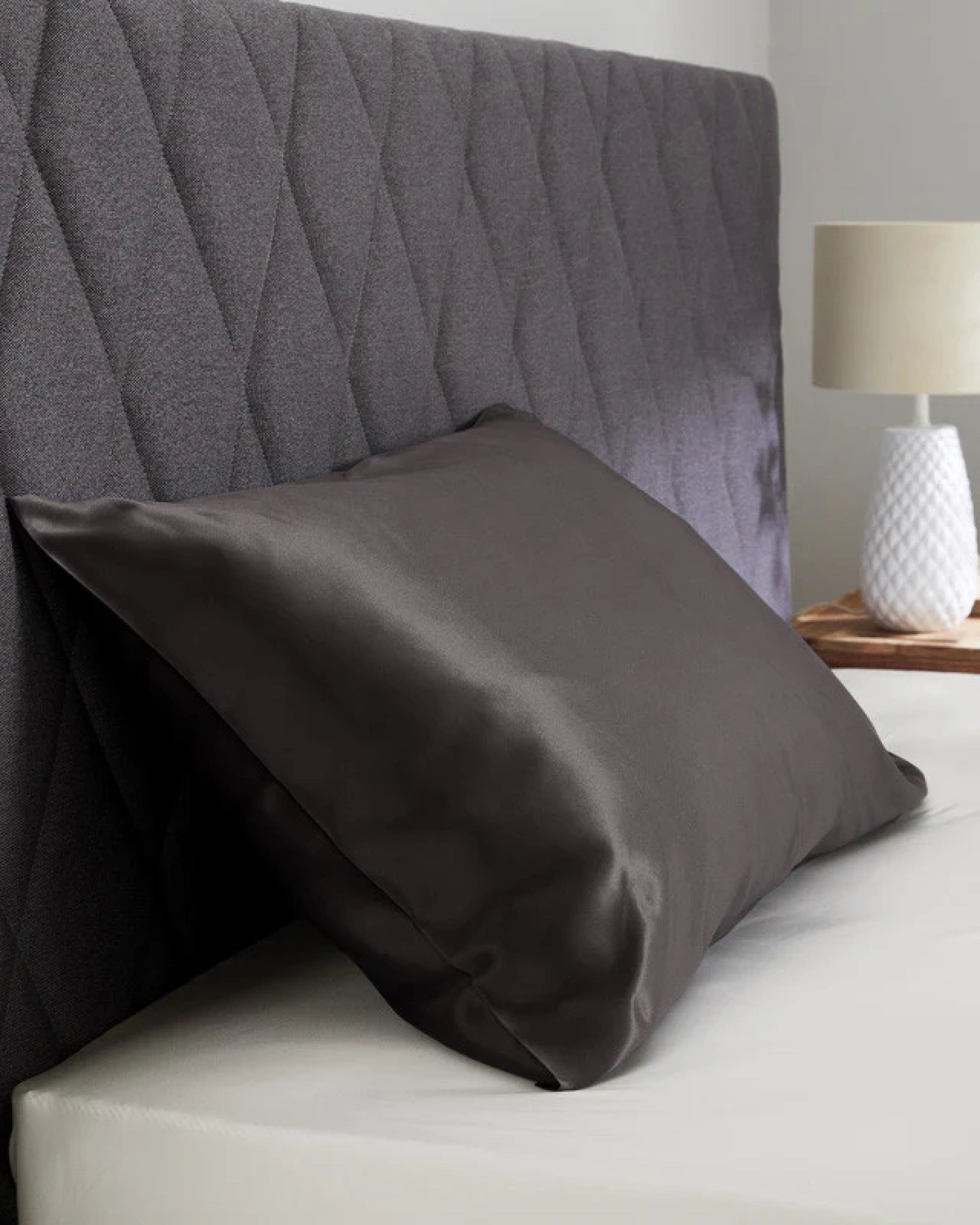 Black velour satin pillowcase on a stylish bed with quilted headboard, enhancing bedroom elegance.